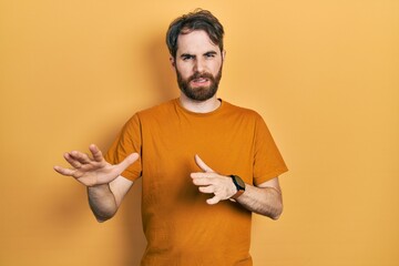 Wall Mural - Caucasian man with beard wearing casual yellow t shirt disgusted expression, displeased and fearful doing disgust face because aversion reaction.