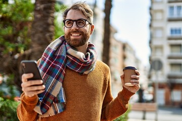 Wall Mural - young caucasian man with beard  using smartphone outdoors on a sunny day