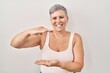 © Krakenimages.com - Middle age caucasian woman standing over white background gesturing with hands showing big and large size sign, measure symbol. smiling looking at the camera. measuring concept.