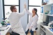 © Krakenimages.com - Man and woman scientist partners high five with hands raised up at laboratory