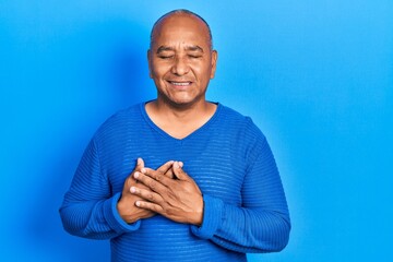 Wall Mural - Middle age latin man wearing casual clothes smiling with hands on chest with closed eyes and grateful gesture on face. health concept.