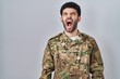 © Krakenimages.com - Arab man wearing camouflage army uniform angry and mad screaming frustrated and furious, shouting with anger. rage and aggressive concept.