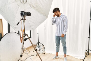 Wall Mural - Arab young man posing as model at photography studio tired rubbing nose and eyes feeling fatigue and headache. stress and frustration concept.