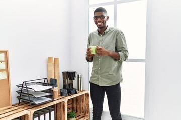 Wall Mural - Young african american man smiling confident drinking coffee at office