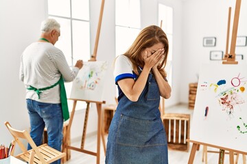 Sticker - Hispanic woman wearing apron at art studio with sad expression covering face with hands while crying. depression concept.