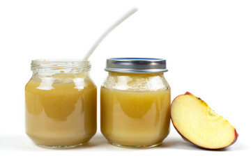 Wall Mural - Two glass jars with baby apple puree with a spoon, a gooseberry and an apple slice on a white isolated background. The first fruit lure, baby food.