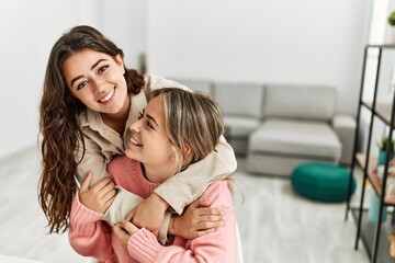 Poster - Young beautiful couple sitting on the chair hugging at home.