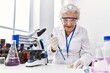 © Krakenimages.com - Senior grey-haired woman wearing scientist uniform using pipette at laboratory