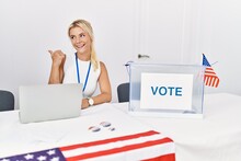 Young Caucasian Woman At America Political Campaign Election Smiling With Happy Face Looking And Pointing To The Side With Thumb Up.