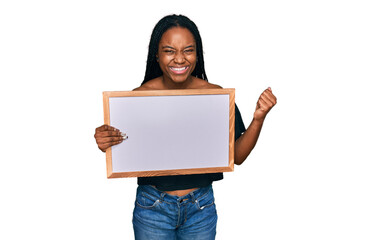 Sticker - Young african american woman holding empty white chalkboard screaming proud, celebrating victory and success very excited with raised arms