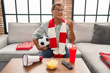 Sticker - Senior man watching football holding ball supporting team pointing thumb up to the side smiling happy with open mouth