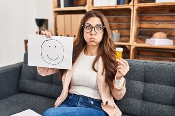 Sticker - Young brunette woman at consultation office puffing cheeks with funny face. mouth inflated with air, catching air.