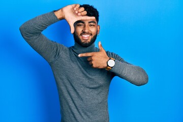 Poster - Arab man with beard wearing turtleneck sweater smiling making frame with hands and fingers with happy face. creativity and photography concept.