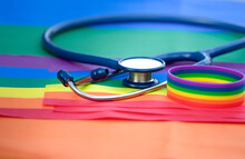 Stethoscope And Rainbow Lgbt Wristband On Lgbt Flags Background, Concept For Medical Support Lgbtq Pride Month, Lgbtq Equality Community  Movement