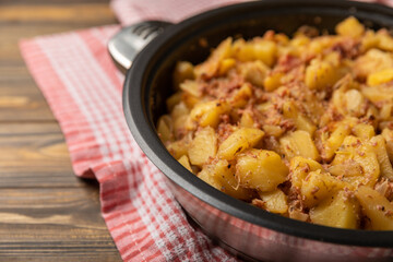 Braised pork with potatoes and onions on a brown wood. Composition with vegetables. Place to copy. Place for text. Fried potato recipe.