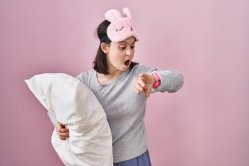 Canvas Print - Woman with down syndrome wearing sleeping mask hugging pillow looking at the watch time worried, afraid of getting late