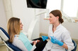 © Tania - A beautiful female dentist is talking to a patient while sitting in a chair.