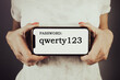 Woman holding phone with weak password qwerty123. Cybersecurity breach risk concept
