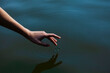 a woman's hand gently touches the water in the pond, a close horizontal photo on the theme of tranquility