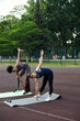 © etonastenka - Two women of different nationalities warm up before training outdoors. Warming up muscles before strength training or jogging