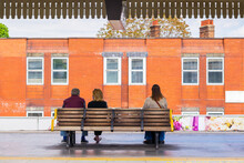 Three People Sitting On A Bench In A Subway Station In London Waiting