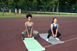 © etonastenka - Young diverse friends squat at the stadium, warm up before performing group exercises