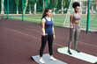 © etonastenka - Happy women exercising with dumbbells outdoors. Fitness women doing a workout in the stadium and working out with small dumbbells