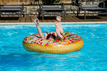 Wall Mural - pretty young girl jumping or diving in her donut shaped buoy