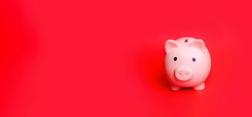 Pink piggy bank isolated against red background