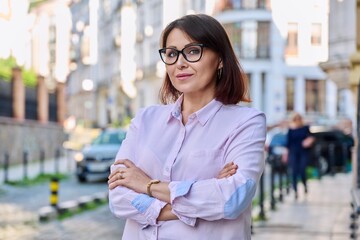 Wall Mural - Portrait of positive confident middle aged woman looking at camera outdoor