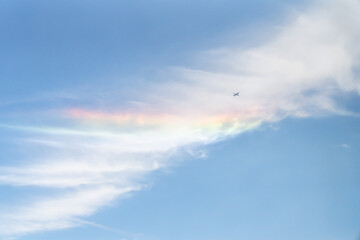 Wall Mural - beautiful sky background photograph of an airplane flying past a partial rainbow reflecting on the w