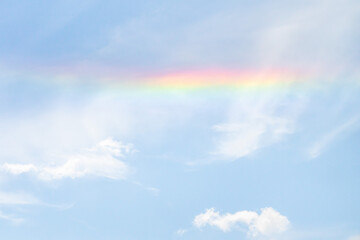 Wall Mural - beautiful sky background photograph of a partial rainbow reflecting on the white clouds in the sky o