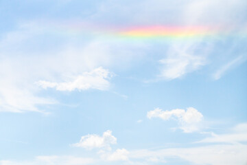 Wall Mural - beautiful sky background photograph of a partial rainbow reflecting on the white clouds in the sky o