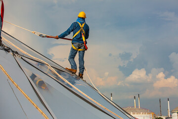 Male workers rope access height safety connecting with a knot safety harness, clipping into roof construction site oil tank dome