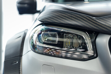 Wall Mural - Close-up headlights of a modern silver color car. Detail on the front light of a car. Modern and expensive car concept. The car is in the showroom. Automotive concept. Classic silver color. LED light