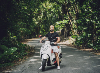 Wall Mural - Stylish young man and his motorbike on the road in the jungle