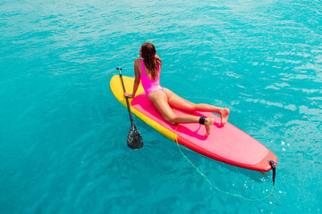 Wall Mural - Beautiful woman posing on Paddle board in blue sea. SUP boarding in ocean