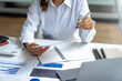 © crizzystudio - Business woman hand pointing business document and analysis data the charts and graphs at desk.