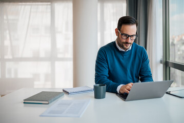 Wall Mural - serious young male professional working on laptop while sitting at office