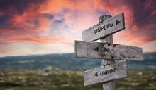 Unplug To Unwind Text Quote Caption On Wooden Signpost Outdoors In Nature With Dramatic Sunset Skies. Panorama Crop.