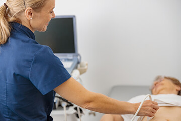 Wall Mural - Close up of doctor ultrasound examine senior patient abdomen at hospital. Prenatal diagnosis center
