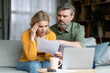 © Prostock-studio - Stressed Middle Aged Spouses Checking Financial Papers At Home