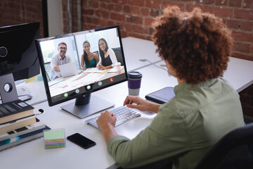 Poster - african american businessman with afro hair discussing online with coworkers over computer in office