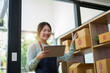 © Jirapong - A portrait of a small startup, an SME owner, an Asian female entrepreneur checking orders to arrange the produce before packing the products in the inner boxes with the customers. Freelance concepts