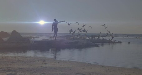 Sticker - Bright spot of light against african american enjoying on the rocks near the sea