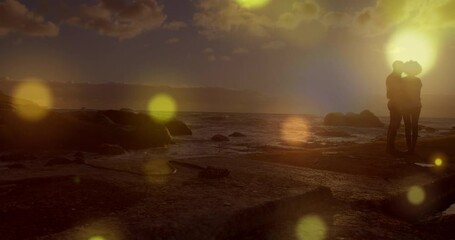 Wall Mural - Glowing yellow spots of light falling against african american couple standing together on the rocks