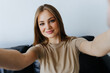 © F8  \ Suport Ukraine - Portrait of beautiful woman taking a self-portrait with her smartphone at home.
