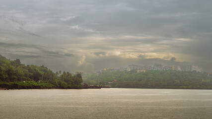 Beautiful monsoon landscape in Goa India from the San Jacinto island with ship building activities and barges docked on the port.