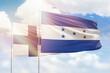 Sunny blue sky and flags of honduras and finland