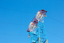 High Voltage Electric Power Lines On Pylons In Blue Sky.